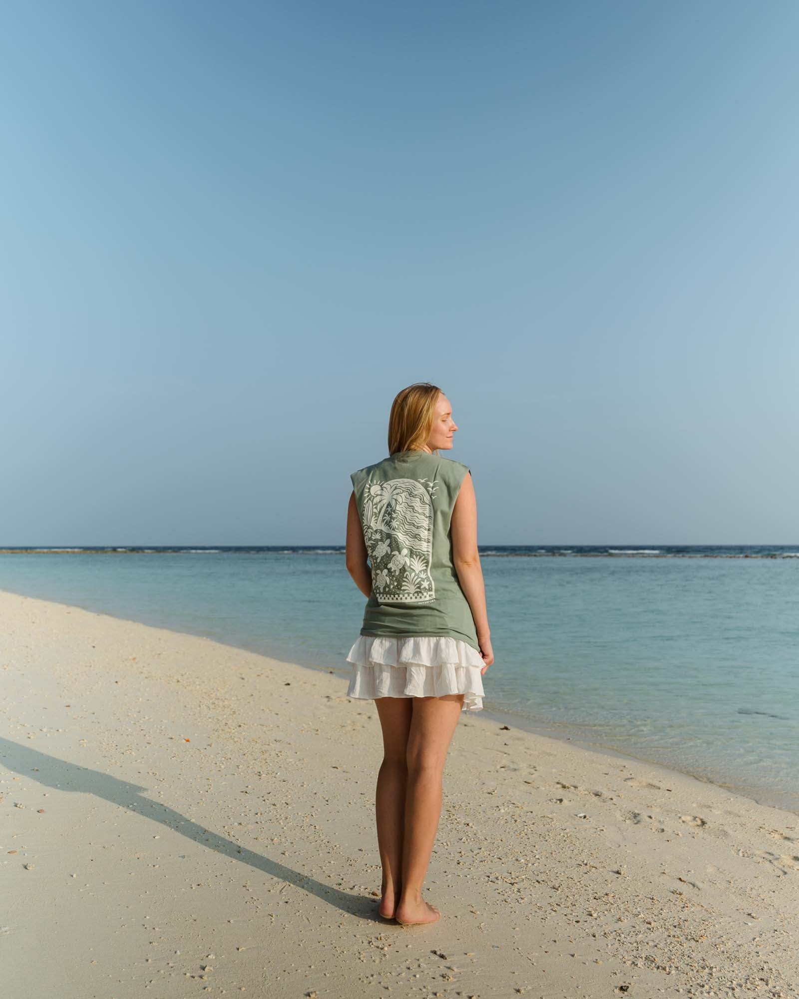 Female wearing the Slow Living Tank Top while standing near a ocean