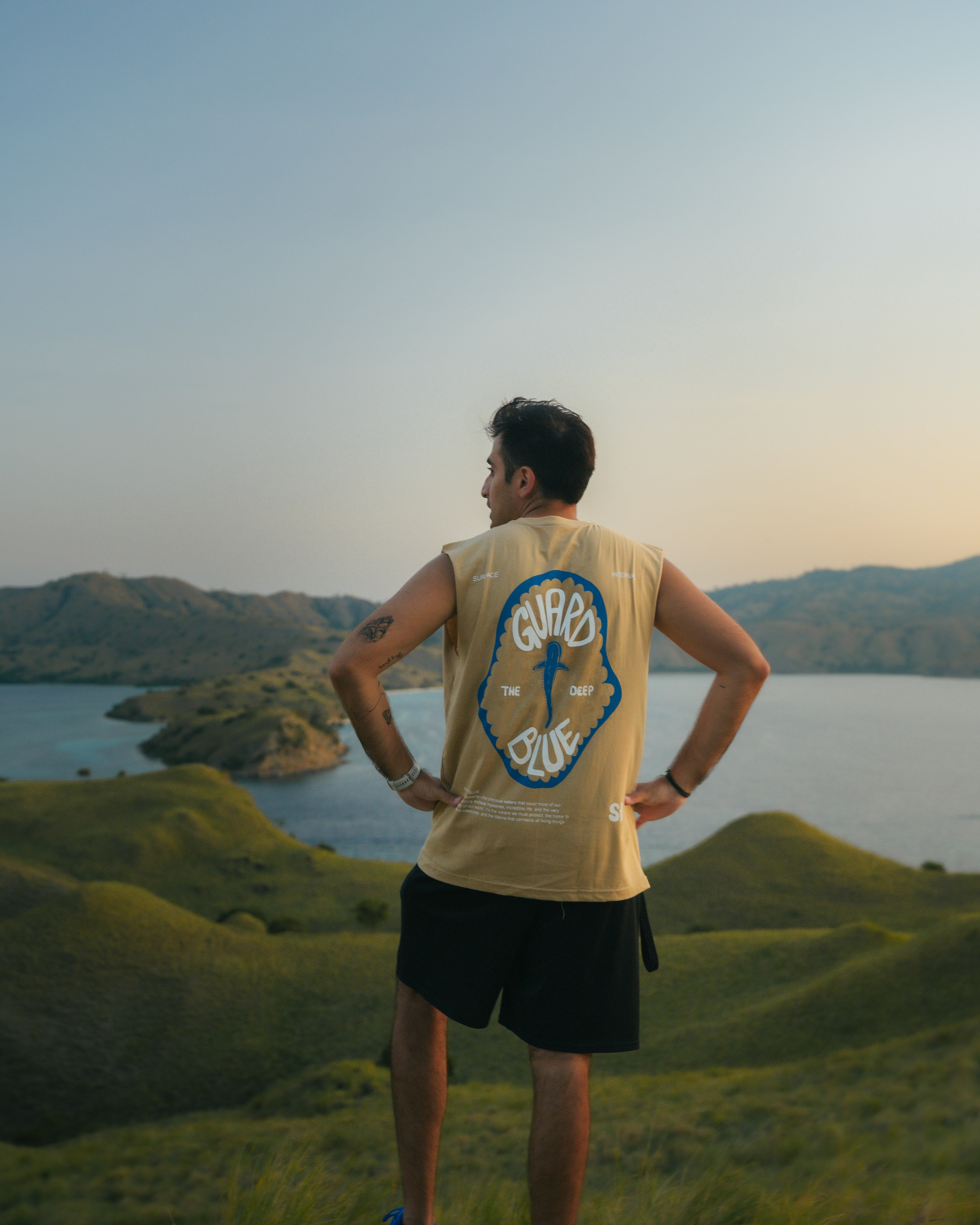 Male model wearing Surface Interval’s Born from Komodo tank top, back view showing ocean-inspired minimalist design and sustainable fit.