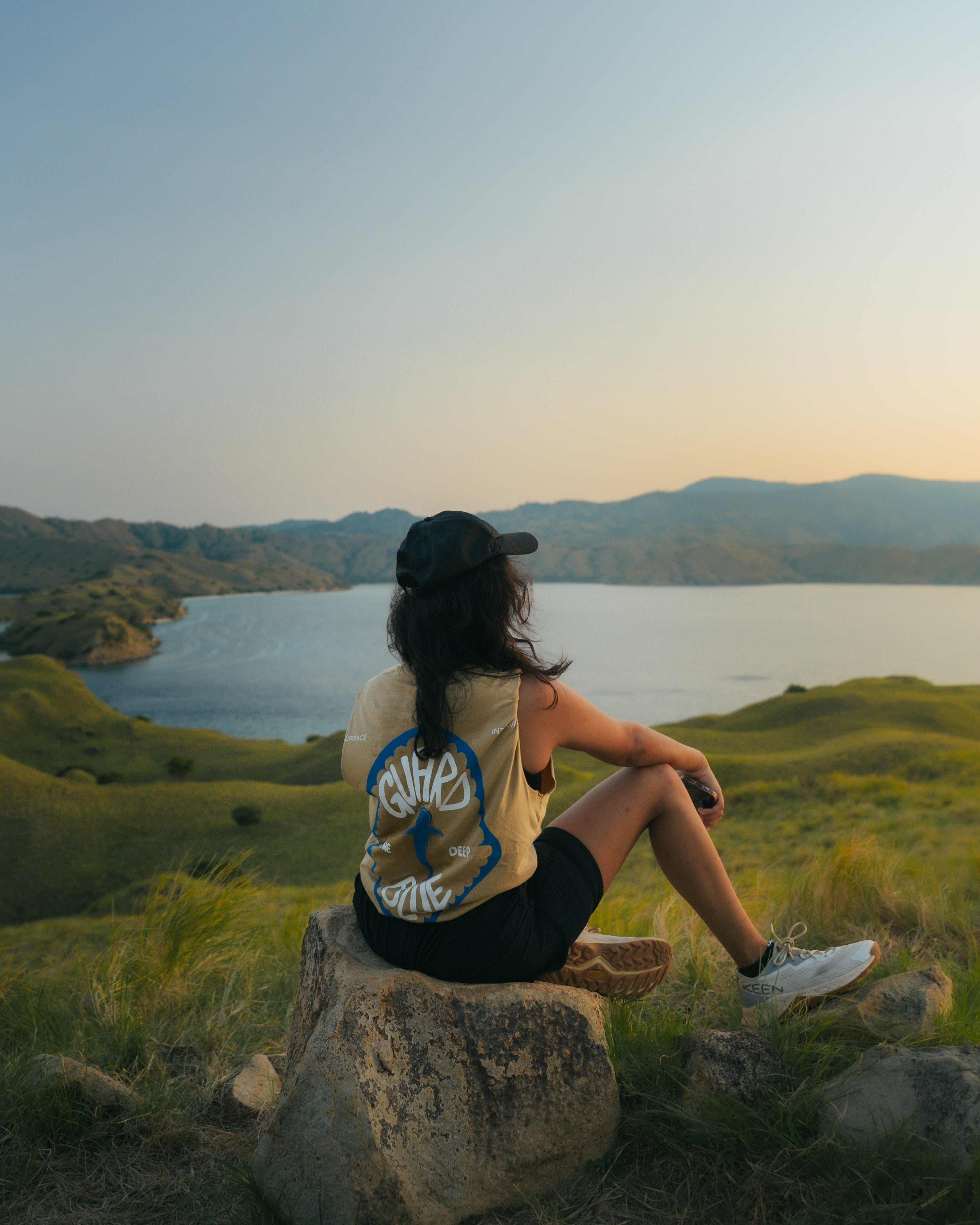 Female model wearing the Surface Interval Komodo tank top in a natural outdoor setting, representing sustainable clothing for ocean lovers.